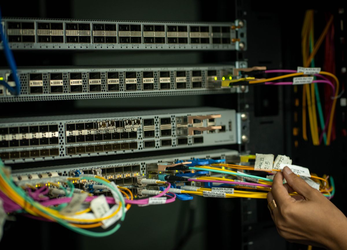 Hands cabling a network switch in a server rack